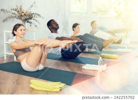 Sporty young woman performing Navasana in yoga studio Sporty young woman performing Navasana in yoga studio 142255702