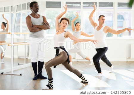 Group of men and women of different nationalities practice ballet moves in dance school Group of men and women of different nationalities practice ballet moves in dance school 142255800