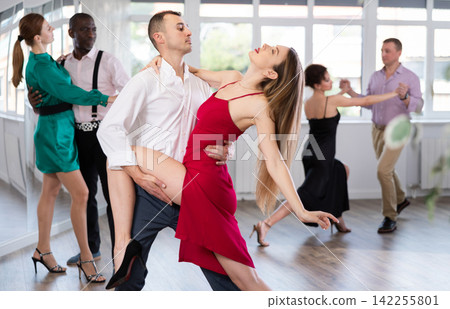 Adult couples spin to rumba rhythm during group dance lesson for beginners Adult couples spin to rumba rhythm during group dance lesson for beginners 142255801
