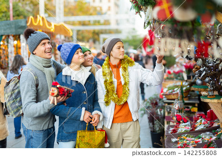 Friendly family chooses Christmas souvenirs and toys Friendly family chooses Christmas souvenirs and toys 142255808