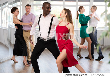 Woman with African man dancing waltz in couple during lesson at studio 142255809