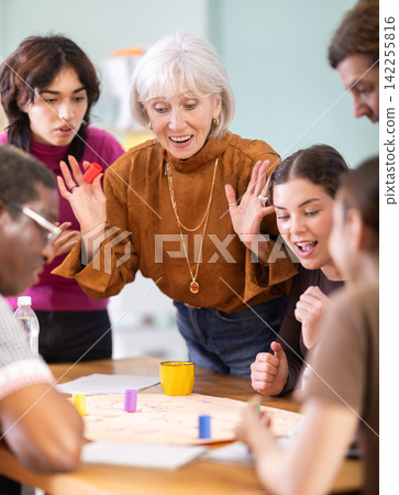Group of focused people playing board game around a table Group of focused people playing board game around a table 142255816