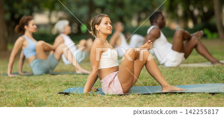 Athletic men and women of different nationalities warm up together before doing yoga in summer park Athletic men and women of different nationalities warm up together before doing yoga in summer park 142255817