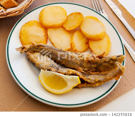 Fried hake served with boiled potatoes and lemon Fried hake served with boiled potatoes and lemon 142255818