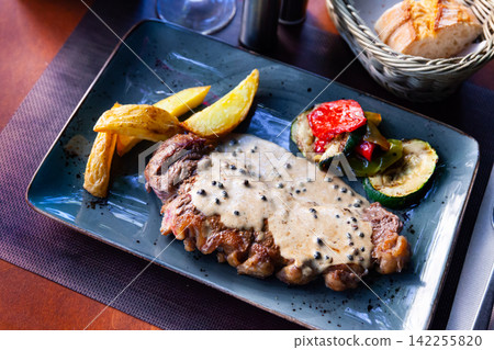 Veal steak with piquant creamy sauce, potatoes and vegetables Veal steak with piquant creamy sauce, potatoes and vegetables 142255820