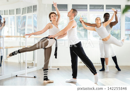 Couple of ballet dancers showcasing supports during group class Couple of ballet dancers showcasing supports during group class 142255846