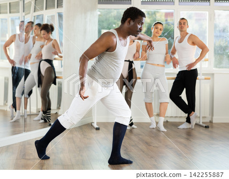 African american man shows ballet positions to a group of students in ballet studio African american man shows ballet positions to a group of students in ballet studio 142255887