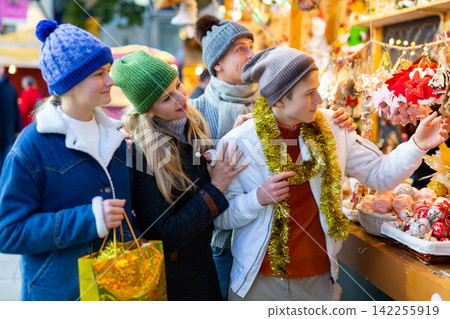 Friendly family chooses Christmas souvenirs and toys Friendly family chooses Christmas souvenirs and toys 142255919