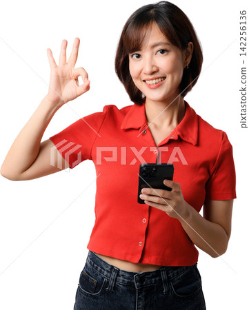 Happy smiling asian woman holding smartphone showing okay gesture wearing red shirt isolated on transparent background cutout stock photo Happy smiling asian woman holding smartphone showing okay gesture wearing red shirt isolated on transparent background cutout stock photo 142256136