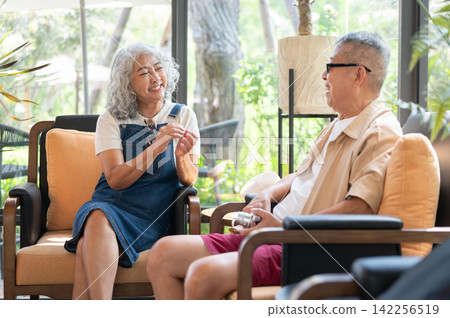 Asian senior couple sharing a pleasant conversation while relaxing together in a comfortable lounge. 142256519