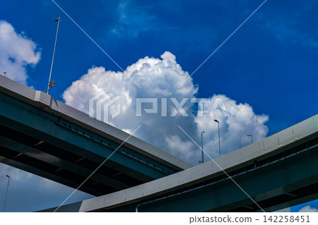 White cumulonimbus clouds stand out against the blue sky and the elevated highway. White cumulonimbus clouds stand out against the blue sky and the elevated highway. 142258451
