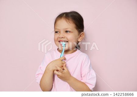 Young child holding a toothbrush, practicing oral hygiene for healthy teeth and developing daily health routine Young child holding a toothbrush, practicing oral hygiene for healthy teeth and developing daily health routine 142258666