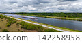 Cargo barge travels along Mittellandkanal through green landscape beneath dramatic summer clouds. Inland waterway supports freight transport, navigation and logistics across northern Germany 142258958