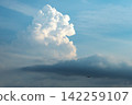 Summer cumulonimbus clouds and an airplane towering against the blue sky. 142259107