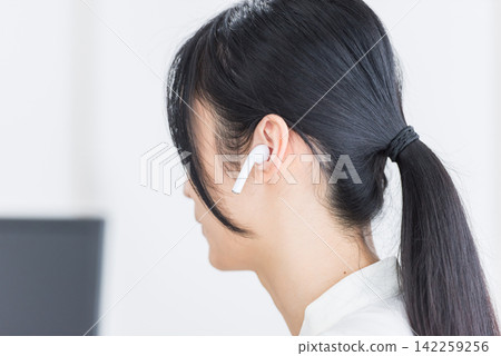 一位女士戴著無線耳機。音樂、通話、無線、聲音、電話、助聽器、音訊、音樂 一位女士戴著無線耳機。音樂、通話、無線、聲音、電話、助聽器、音訊、音樂 142259256
