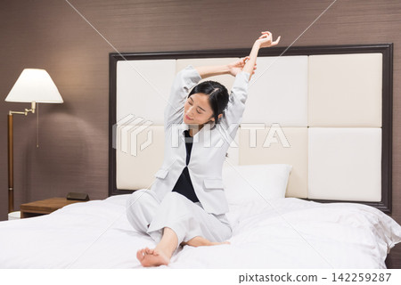 工作在旅館床上放鬆的女商人 工作在旅館床上放鬆的女商人 142259287