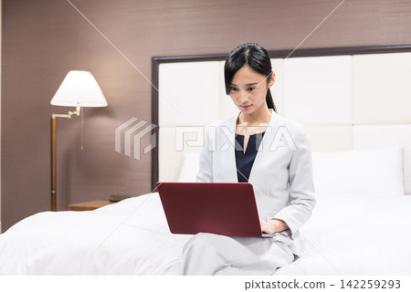 在旅館的床上工作的女商人 142259293