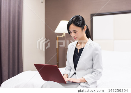 在旅館的床上工作的女商人 在旅館的床上工作的女商人 142259294