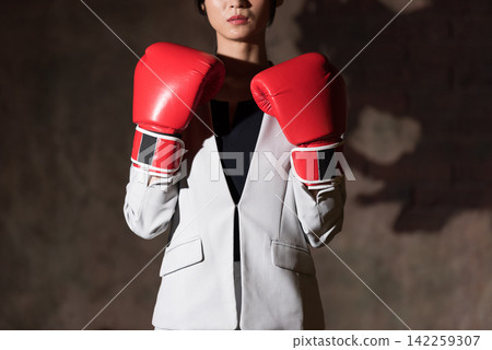 Business woman wearing fighting pose with boxing gloves Business woman wearing fighting pose with boxing gloves 142259307