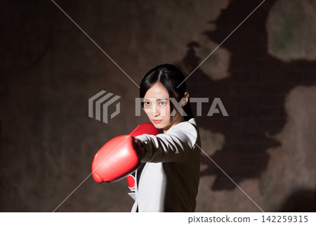 用拳擊手套沖孔的女商人 142259315