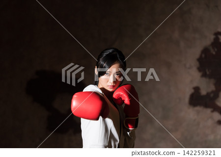 用拳擊手套沖孔的女商人 用拳擊手套沖孔的女商人 142259321