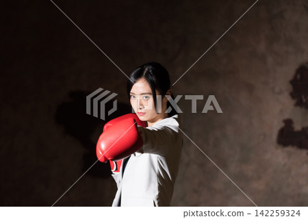 用拳擊手套沖孔的女商人 用拳擊手套沖孔的女商人 142259324