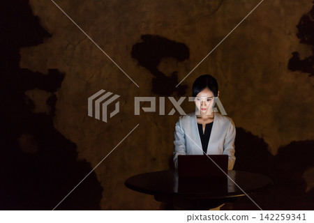 A woman using a computer in a dark room. PC, dark, crime, crime prevention, security, risk, hacker, darkness, internet A woman using a computer in a dark room. PC, dark, crime, crime prevention, security, risk, hacker, darkness, internet 142259341