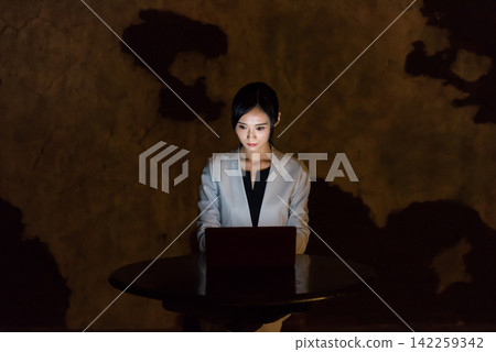 一名女子在黑暗的房間裡使用電腦。個人電腦、黑暗、犯罪、犯罪預防、安全、風險、駭客、互聯網 一名女子在黑暗的房間裡使用電腦。個人電腦、黑暗、犯罪、犯罪預防、安全、風險、駭客、互聯網 142259342