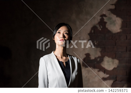 一位女士站在黑暗的房間裡。商業、獨立、焦慮、擔憂、決心、工作、日本、黑暗、未來、陰鬱、冷靜、才華 一位女士站在黑暗的房間裡。商業、獨立、焦慮、擔憂、決心、工作、日本、黑暗、未來、陰鬱、冷靜、才華 142259371