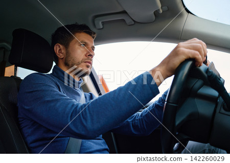 Focused man driving a car wearing a seatbelt Focused man driving a car wearing a seatbelt 142260029