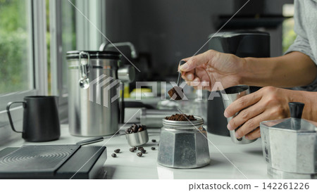 powder coffee on a stainless spoon with hand people pour Roasted coffee for espresso coffee into the cup with equipment tool brewing Italian Moka pot, preparation coffee powder coffee on a stainless spoon with hand people pour Roasted coffee for espresso coffee into the cup with equipment tool brewing Italian Moka pot, preparation coffee 142261226