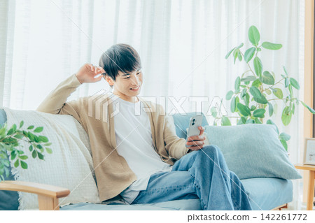 一個男人在客廳看著他的智慧型手機 142261772