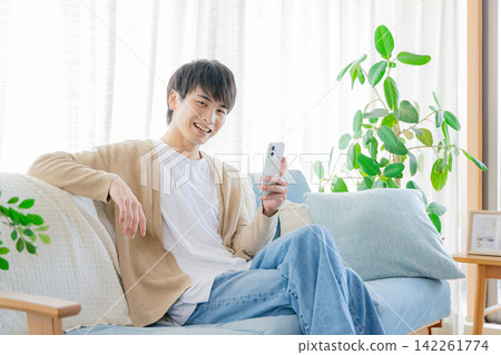 一個男人在客廳看著他的智慧型手機 142261774