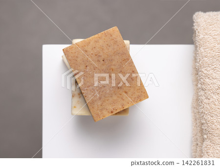 Beige soap basr on white near beige towel. Unbranded packaging Beige soap basr on white near beige towel. Unbranded packaging 142261831
