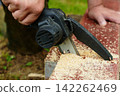Using a battery chainsaw, a worker saws wood. Hard work, step repairs 142262469