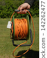 Long orange electrical extension cord 142262477