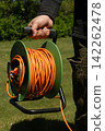 Long orange electrical extension cord 142262478