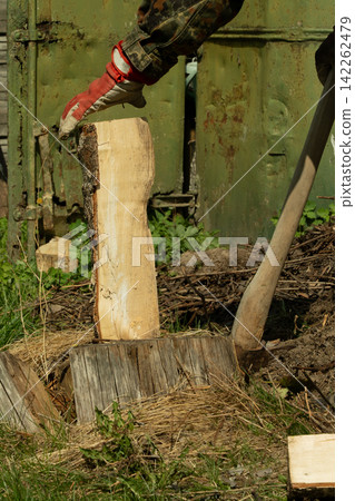 A man chops wood withan axe. Preparing fuelfor the winter 142262479