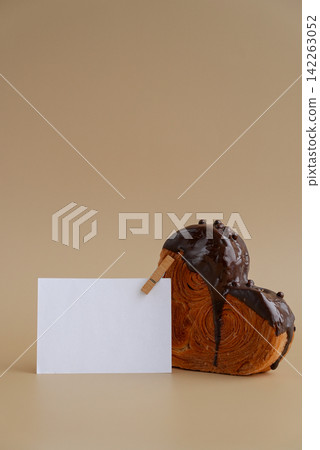 Mock up template paper note card Heart shaped dark chocolate croissant on beige background with copy space. Puff pastry new trendy sweet dessert bakery. Creamy dough Mock up template paper note card Heart shaped dark chocolate croissant on beige background with copy space. Puff pastry new trendy sweet dessert bakery. Creamy dough 142263052
