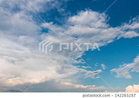 一架飛機飛越廣闊的藍天和雲層。 一架飛機飛越廣闊的藍天和雲層。 142263287