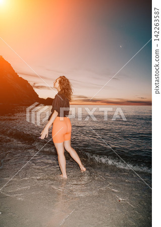 Woman enjoying peaceful evening by the sea at sunset Woman enjoying peaceful evening by the sea at sunset 142263587