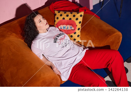 Woman resting comfortably on sofa with fashionable attire Woman resting comfortably on sofa with fashionable attire 142264138