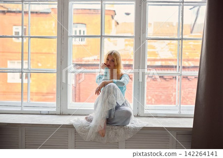 Bright morning light illuminates seated woman watching rooftops Bright morning light illuminates seated woman watching rooftops 142264141