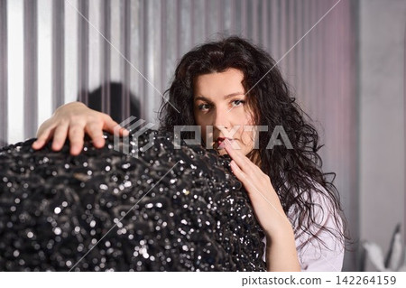 Stylish woman with glittering orb and textured metallic backdrop Stylish woman with glittering orb and textured metallic backdrop 142264159