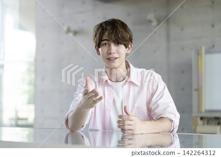 A young foreign man speaking while looking directly at the camera. A young foreign man speaking while looking directly at the camera. 142264312