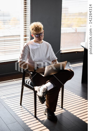 Caucasian teenager concentrating on digital coursework in sunlight Caucasian teenager concentrating on digital coursework in sunlight 142264314