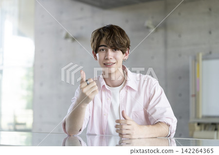 一位年輕的外國男子麵帶微笑,對著鏡頭豎起大拇指。 一位年輕的外國男子麵帶微笑,對著鏡頭豎起大拇指。 142264365
