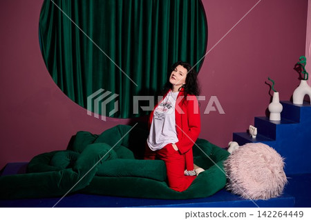 Woman lounges in colorful surroundings with thoughtful expression Woman lounges in colorful surroundings with thoughtful expression 142264449