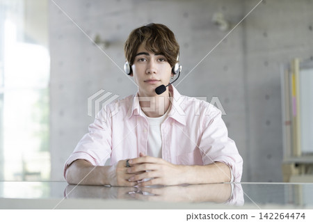 一個年輕的外國男子戴著耳機,看著相機 一個年輕的外國男子戴著耳機,看著相機 142264474