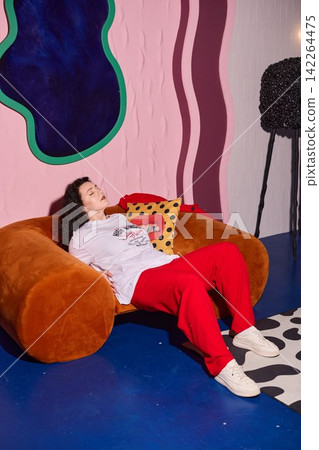 Woman lounging on velvet sofa during casual fitting session Woman lounging on velvet sofa during casual fitting session 142264475